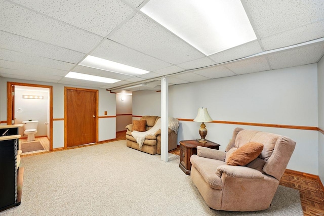 sitting room with baseboards and a drop ceiling