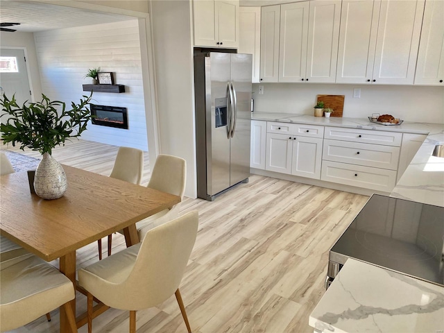 dining space featuring a glass covered fireplace and light wood-style flooring