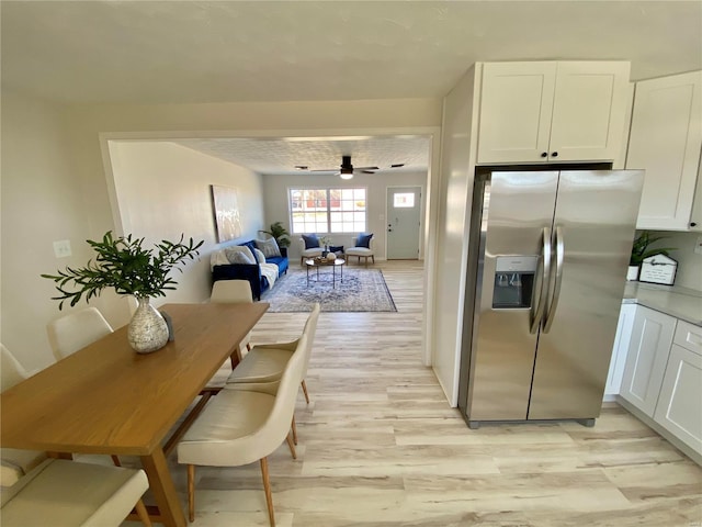 kitchen featuring a ceiling fan, light wood-type flooring, stainless steel fridge, white cabinetry, and open floor plan