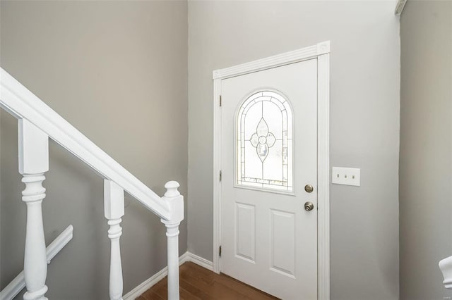 entrance foyer with dark wood-type flooring, stairway, and baseboards