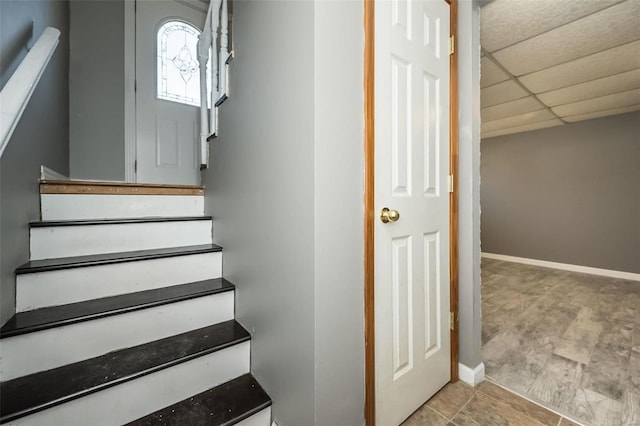 staircase with a drop ceiling and baseboards