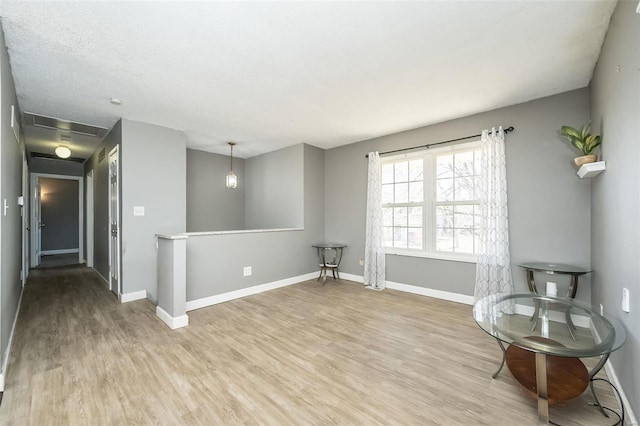 unfurnished room featuring an upstairs landing, baseboards, and light wood-style floors