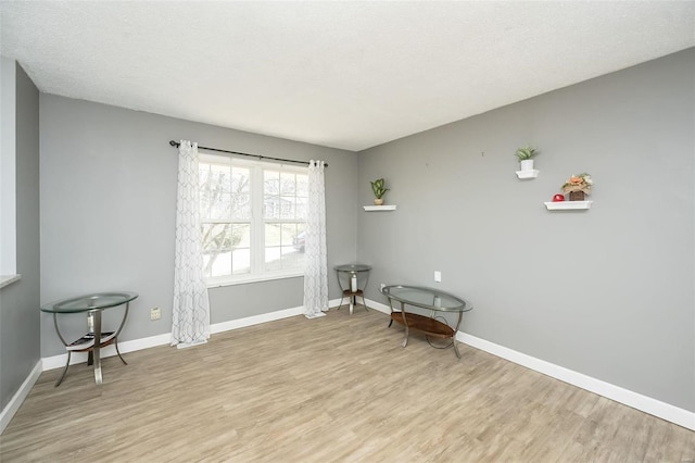 living area with baseboards, a textured ceiling, and wood finished floors