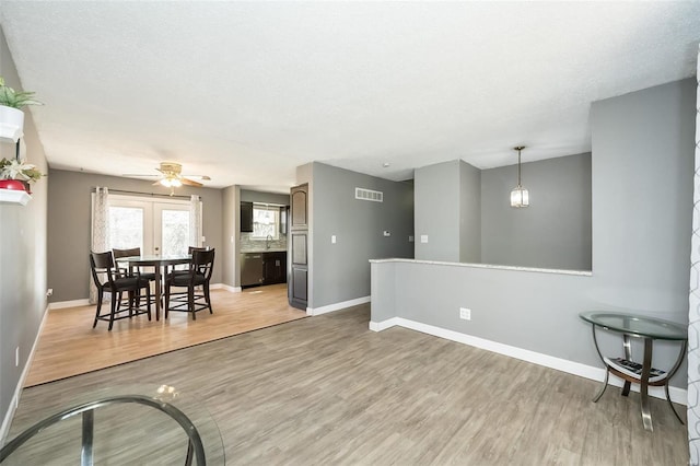 living room with light wood-type flooring, baseboards, and visible vents