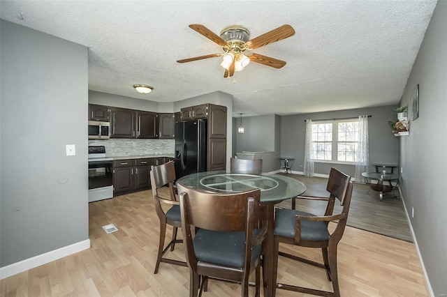 dining room with light wood-style flooring, a textured ceiling, and baseboards