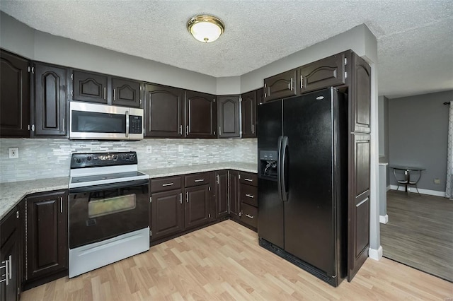 kitchen with stainless steel microwave, black fridge, light wood-style flooring, and range with electric cooktop