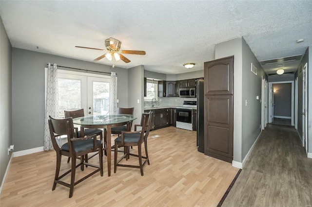 dining room with french doors, baseboards, a textured ceiling, and light wood finished floors