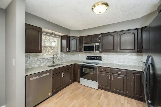 kitchen with dark brown cabinetry, light wood-style floors, appliances with stainless steel finishes, and a sink