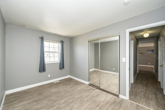 unfurnished bedroom featuring a closet, baseboards, and wood finished floors