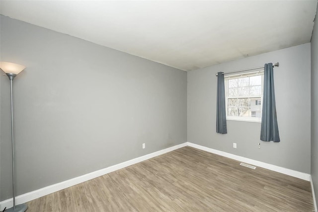 empty room featuring visible vents, baseboards, and wood finished floors