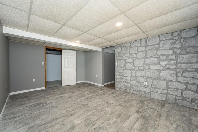 finished below grade area with wood finished floors, baseboards, and a paneled ceiling