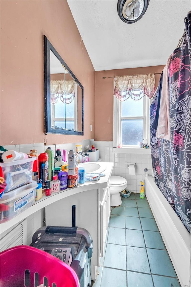 bathroom featuring tile walls, toilet, wainscoting, tile patterned floors, and vanity