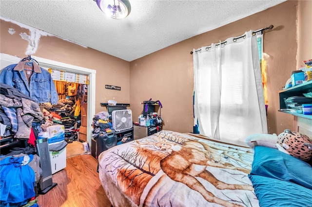 bedroom with a textured ceiling and wood finished floors