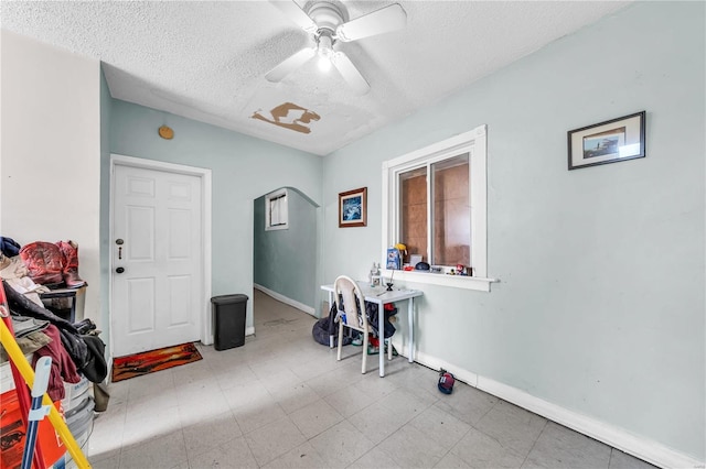 interior space featuring ceiling fan, tile patterned floors, baseboards, and a textured ceiling