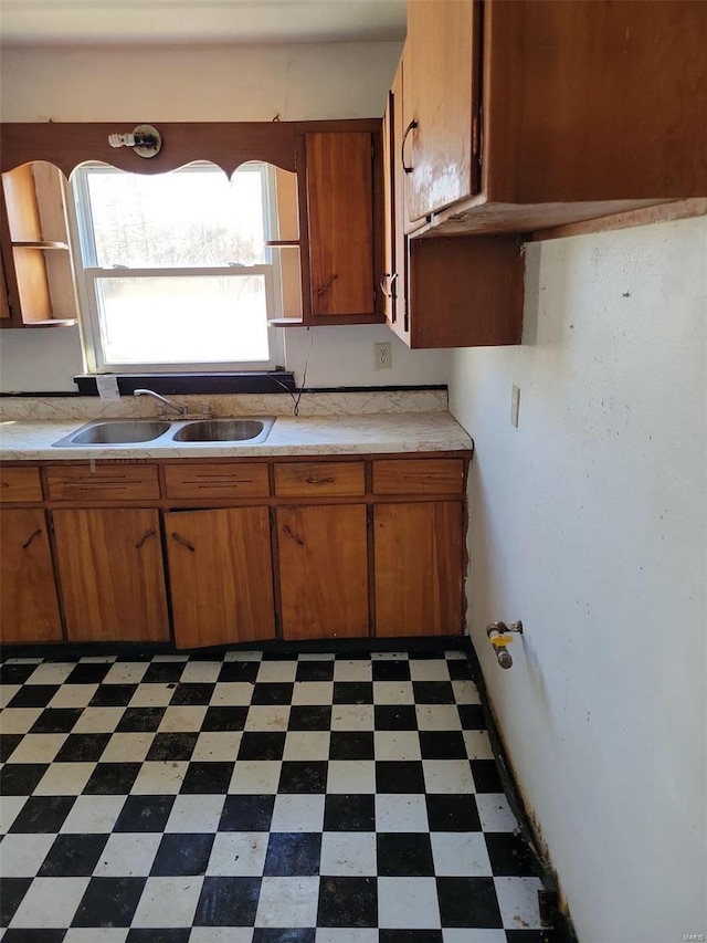 kitchen with a sink, brown cabinets, dark floors, and light countertops