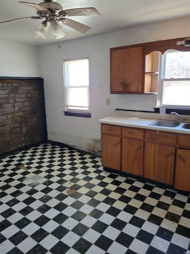 kitchen featuring a sink, light countertops, brown cabinets, a ceiling fan, and open shelves