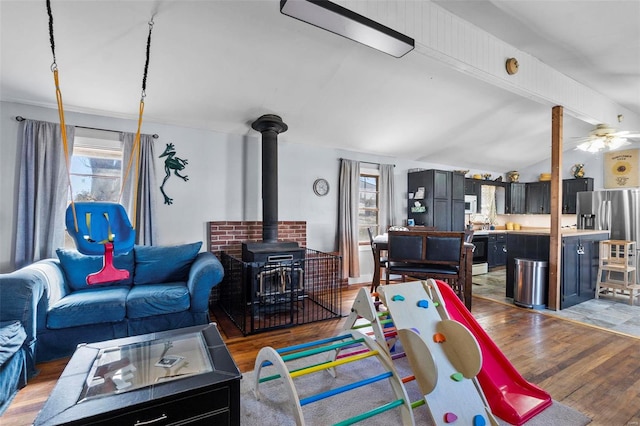 living room with lofted ceiling with beams, plenty of natural light, light wood-style floors, and a wood stove