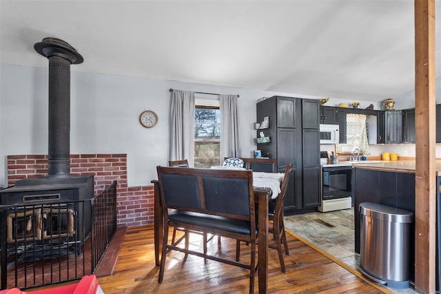 dining space with a wood stove and hardwood / wood-style flooring