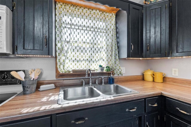 kitchen featuring a sink, white microwave, butcher block countertops, and dark cabinets