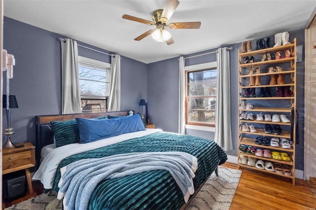 bedroom with multiple windows, wood finished floors, and a ceiling fan