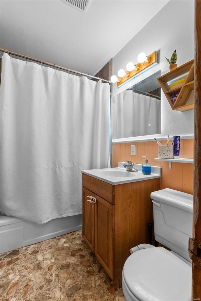 bathroom with curtained shower, toilet, vanity, and stone finish flooring