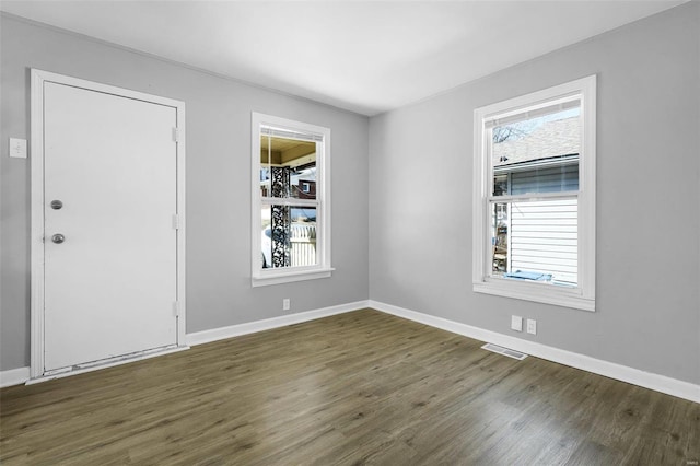 empty room with wood finished floors, visible vents, and baseboards
