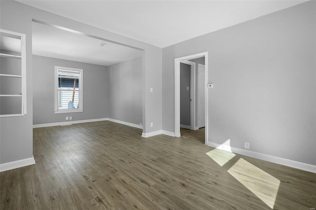 spare room featuring dark wood finished floors and baseboards