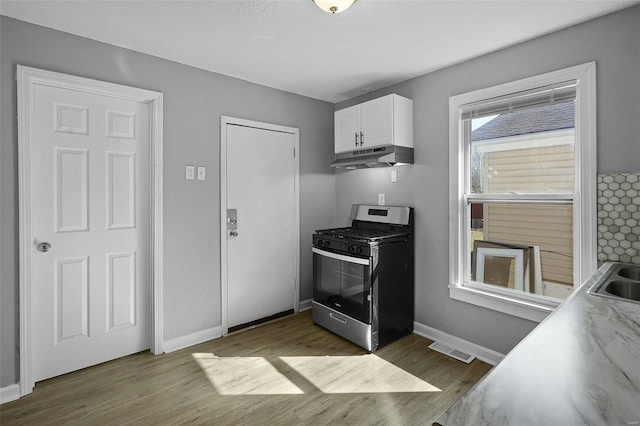 kitchen with visible vents, under cabinet range hood, dark wood finished floors, white cabinetry, and gas range