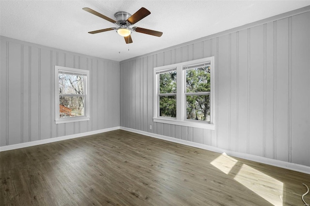 unfurnished room with plenty of natural light, ceiling fan, and wood finished floors