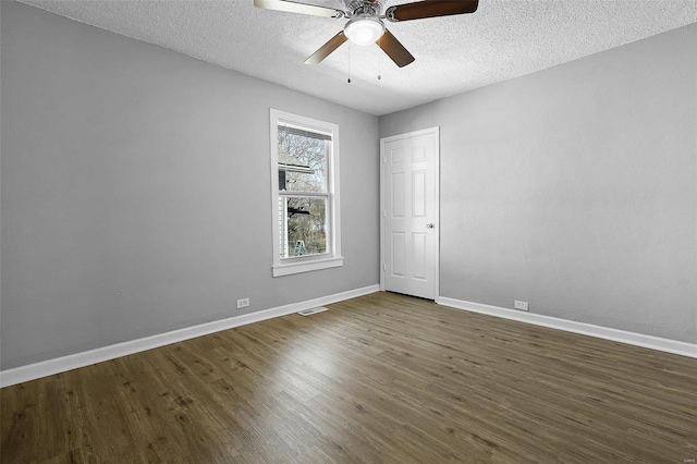 empty room featuring baseboards, dark wood-type flooring, ceiling fan, and a textured ceiling