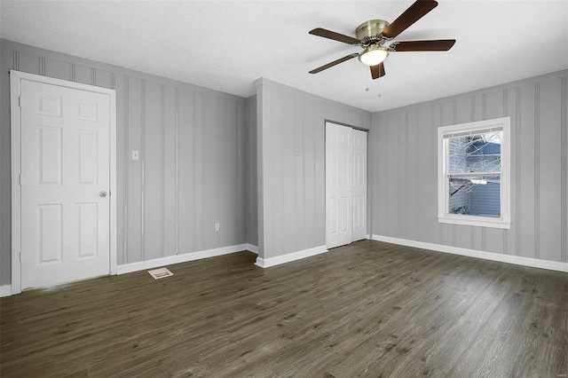 unfurnished bedroom featuring baseboards, visible vents, dark wood finished floors, ceiling fan, and a closet