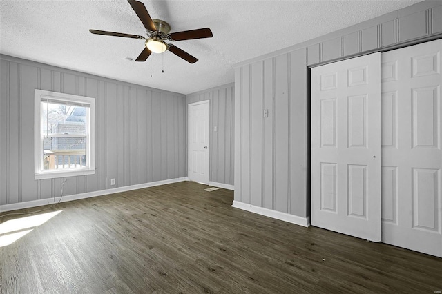 unfurnished bedroom featuring dark wood finished floors, ceiling fan, a textured ceiling, and baseboards