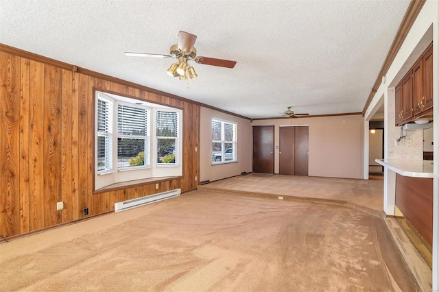 unfurnished living room featuring a baseboard heating unit, wooden walls, ornamental molding, and light carpet