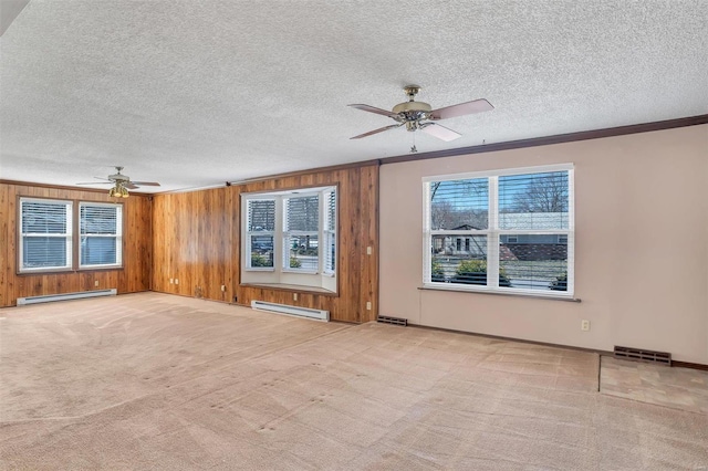 unfurnished living room featuring visible vents, baseboard heating, wood walls, and carpet