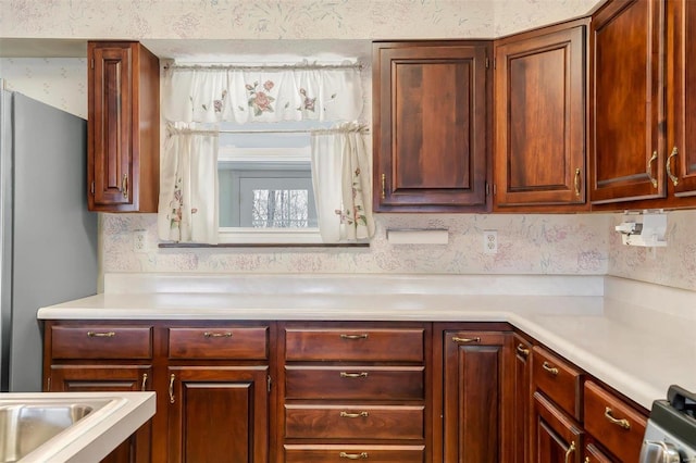 kitchen with light countertops, gas range oven, and freestanding refrigerator