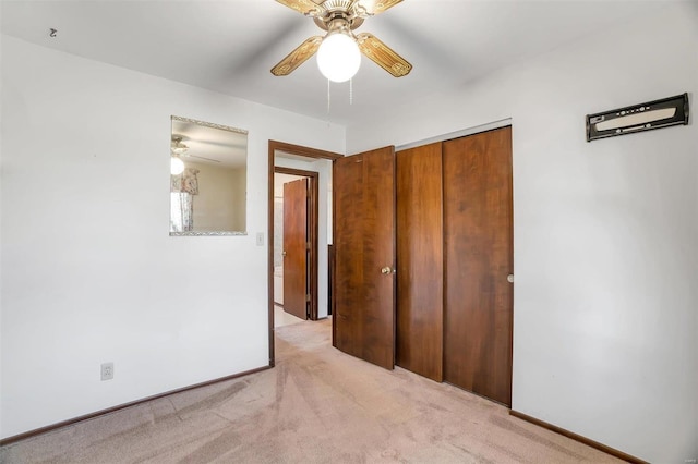 unfurnished bedroom with a closet, light colored carpet, baseboards, and ceiling fan