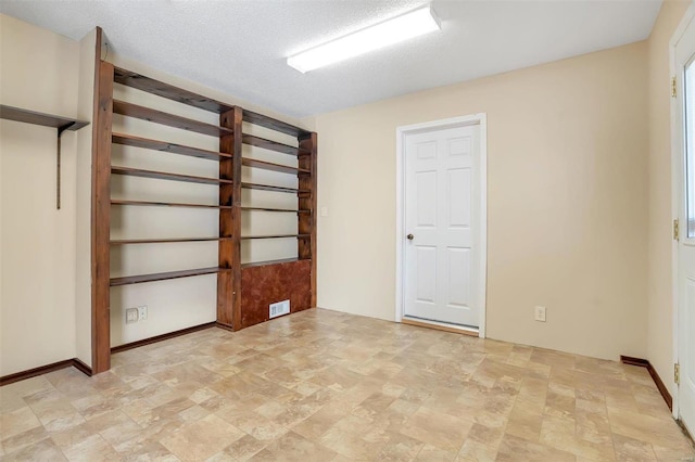 empty room featuring visible vents, a textured ceiling, and stone finish flooring