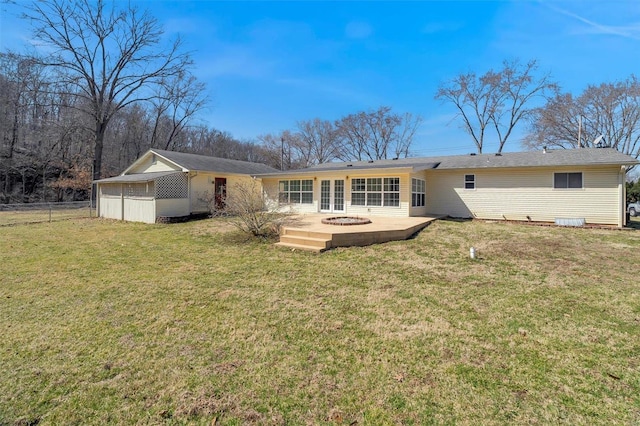 back of house featuring fence, a lawn, and an outdoor fire pit