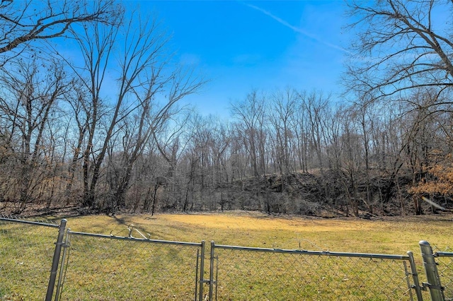 view of yard with a gate, a view of trees, and fence