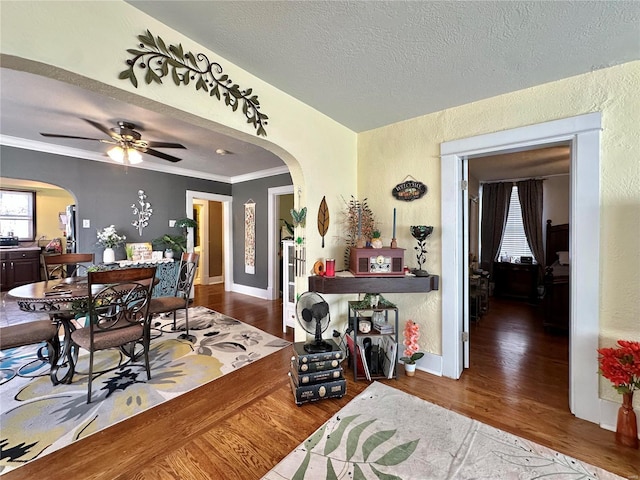 dining area with wood finished floors, arched walkways, a textured wall, and a textured ceiling