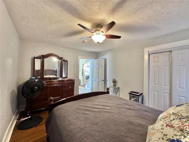 bedroom featuring baseboards, ceiling fan, dark wood-type flooring, a closet, and a textured ceiling