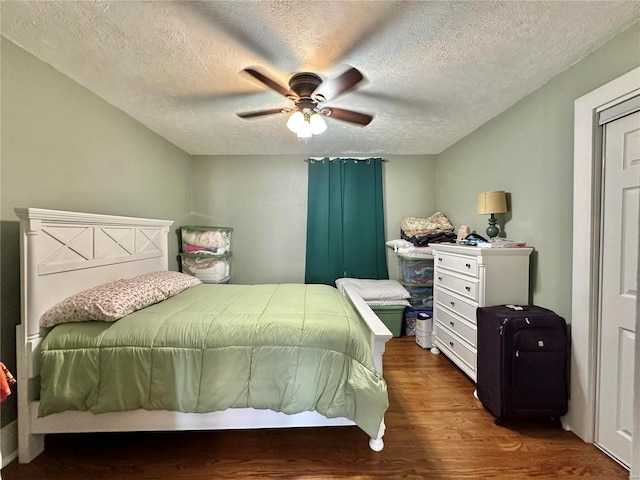 bedroom with ceiling fan, a textured ceiling, and wood finished floors