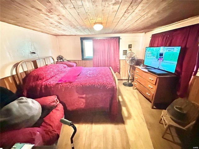 bedroom featuring wooden walls, wainscoting, wooden ceiling, and wood finished floors