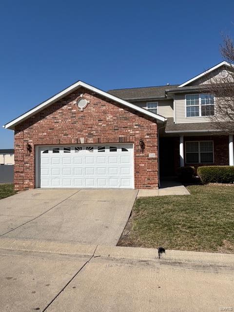 view of front facade with brick siding, an attached garage, concrete driveway, and a front lawn