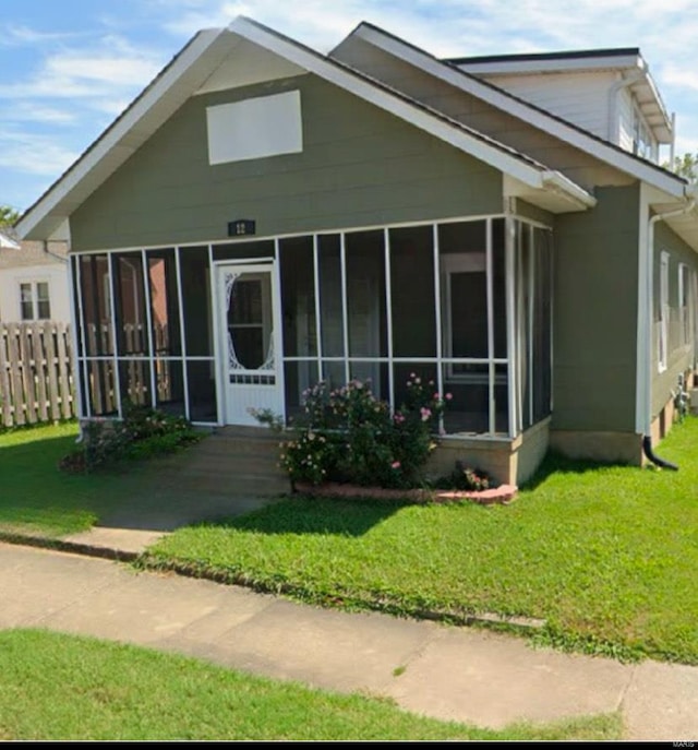 view of front of property with a sunroom, a front lawn, and fence