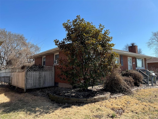 exterior space featuring fence, brick siding, and a chimney