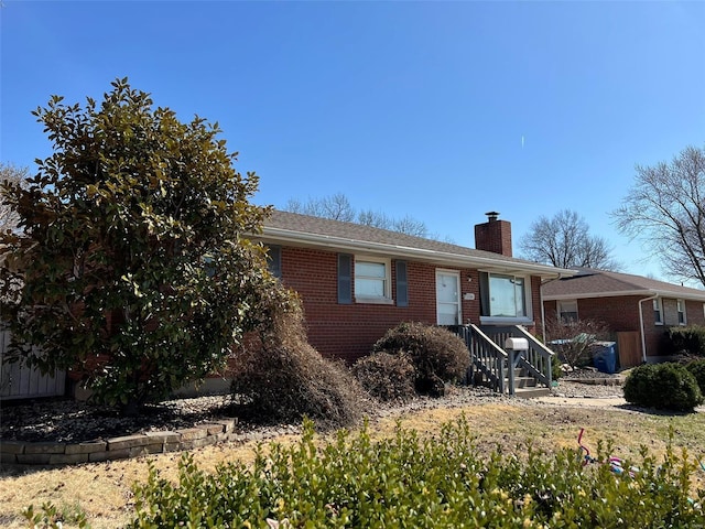 ranch-style house featuring brick siding and a chimney