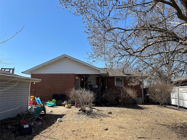 exterior space with brick siding, a porch, and fence