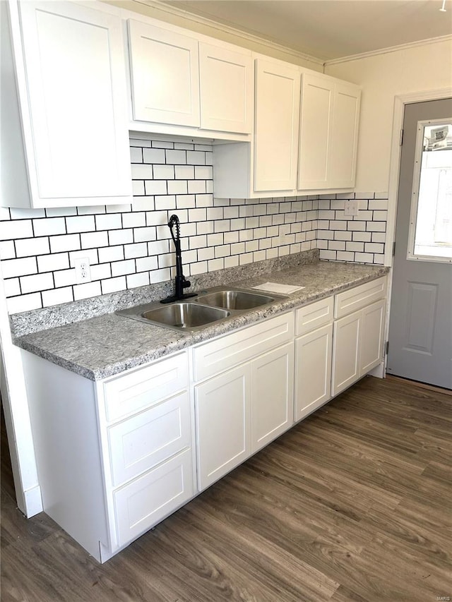 kitchen featuring a sink, decorative backsplash, dark wood-type flooring, white cabinets, and crown molding