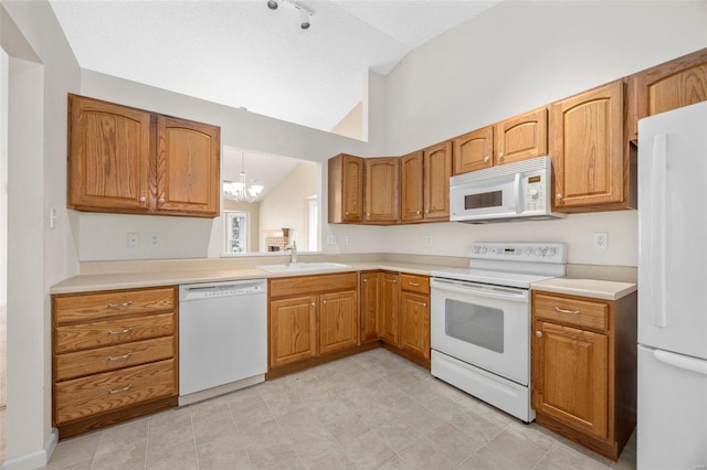 kitchen featuring white appliances, an inviting chandelier, a sink, vaulted ceiling, and brown cabinets